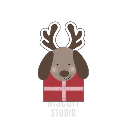 Cookie cutter design of a dog with reindeer antlers wearing a red gift box costume by Biscuit Studio.