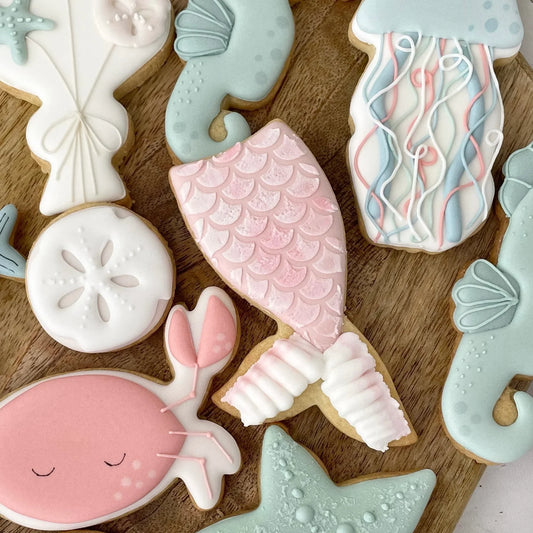 Sea-themed decorated cookies including mermaid tail, seahorse, jellyfish, and starfish shapes.